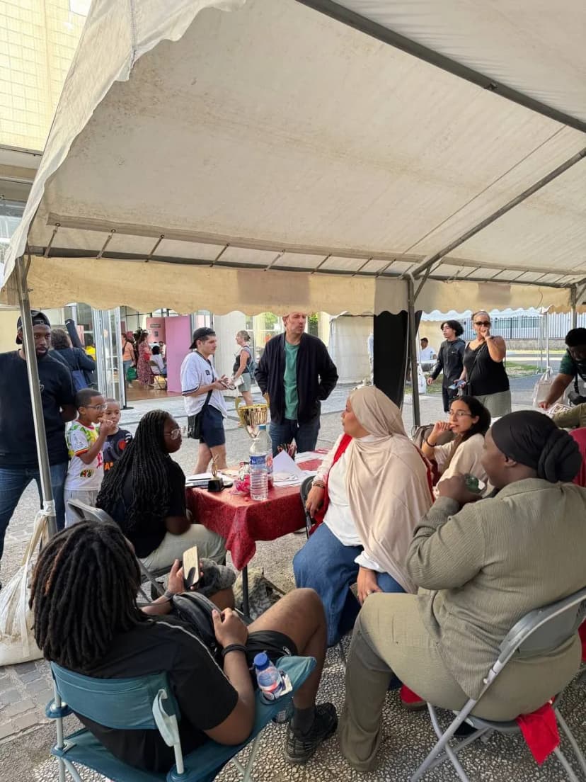 Sous une tente, des personnes assises autour d’une table discutent lors du forum des associations.