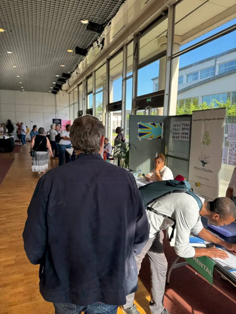 Dans un hall vitré, des visiteurs circulent entre les stands du forum des associations.