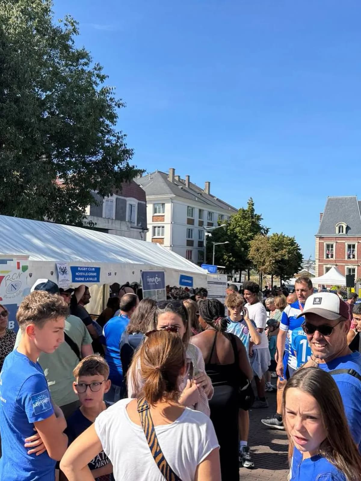 La foule du forum des associations devant un chapiteau et des stands, par temps ensoleillé.