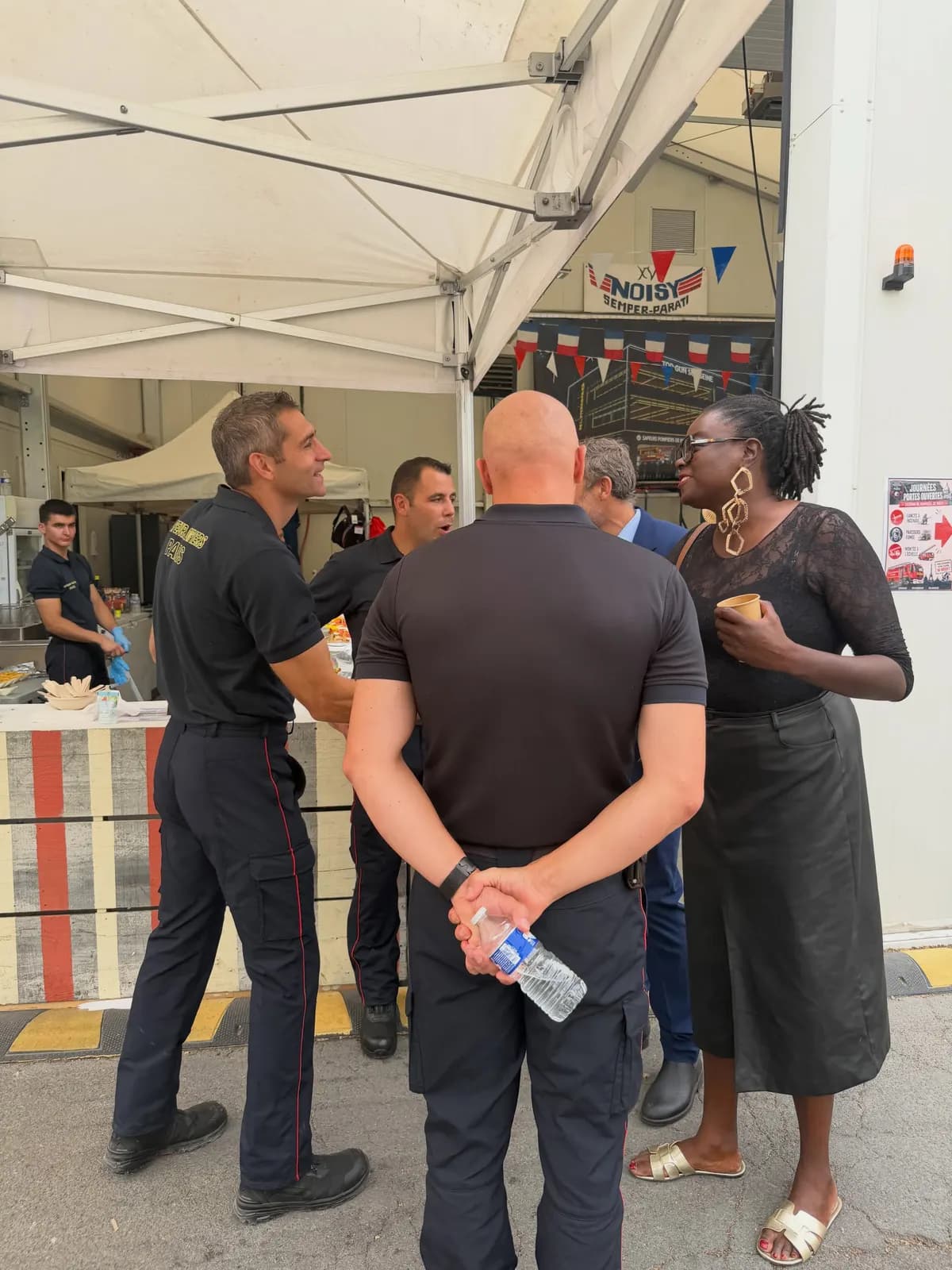 Sous un barnum, un pompier en tenue s’entretient avec trois personnes venues au stand.