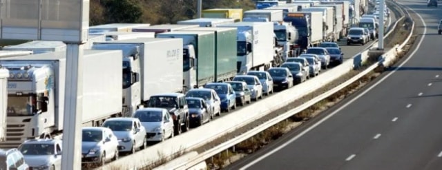 File de poids lourds et de voitures à l’arrêt sur une autoroute à deux fois deux voies.