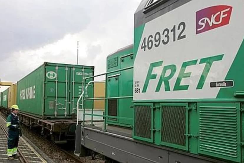 Locomotive verte Fret SNCF en tête d’un train de conteneurs, un agent marchant le long de la voie.