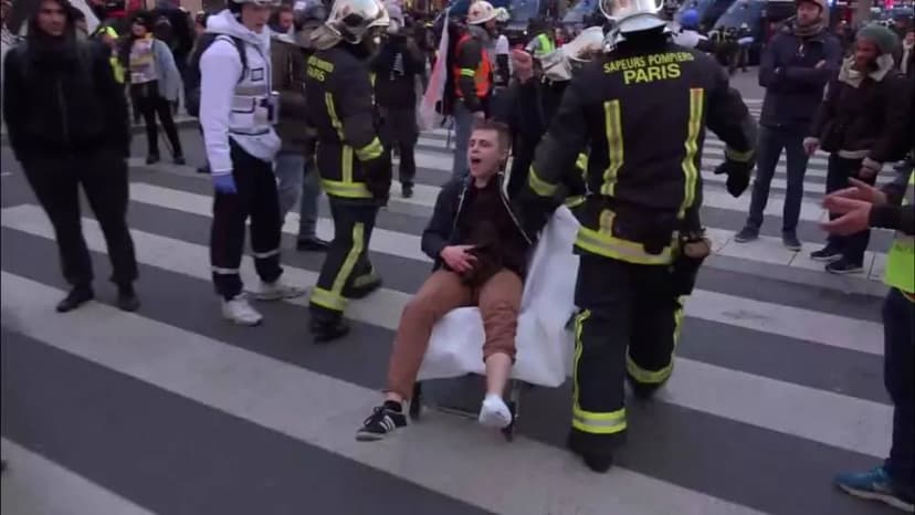 Des sapeurs-pompiers de Paris portent sur une chaise un jeune homme blessé qui crie, au milieu d’une foule.