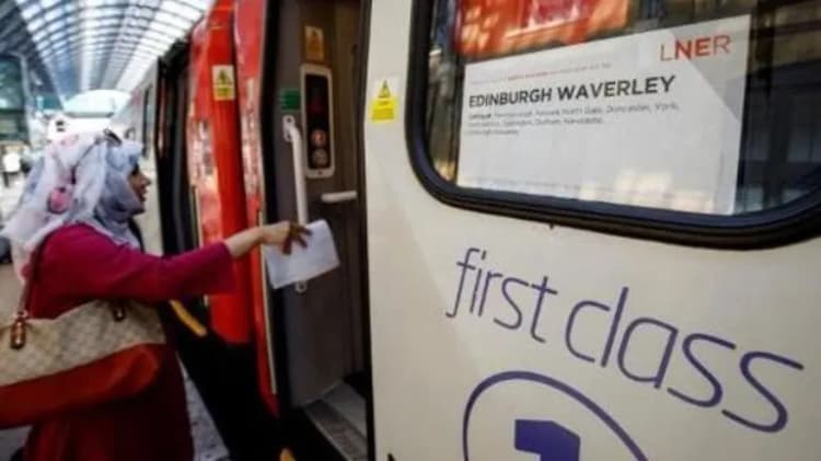 Une voyageuse monte à bord d’une voiture de première classe portant la destination Edinburgh Waverley.