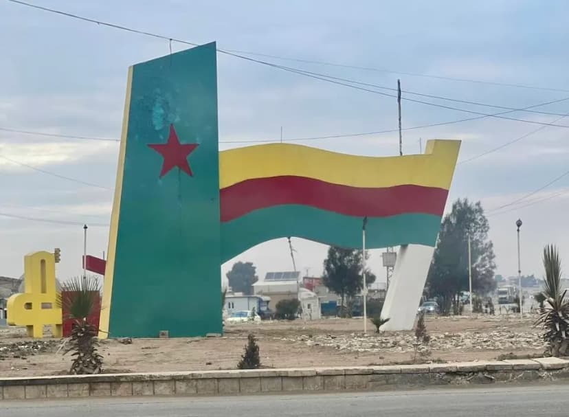 Monument de bord de route figurant un drapeau peint aux couleurs vert, jaune et rouge, étoile rouge sur fond vert.