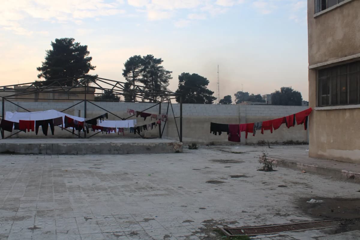 Cour d’un bâtiment où sèche du linge sur des fils tendus, en fin de journée.