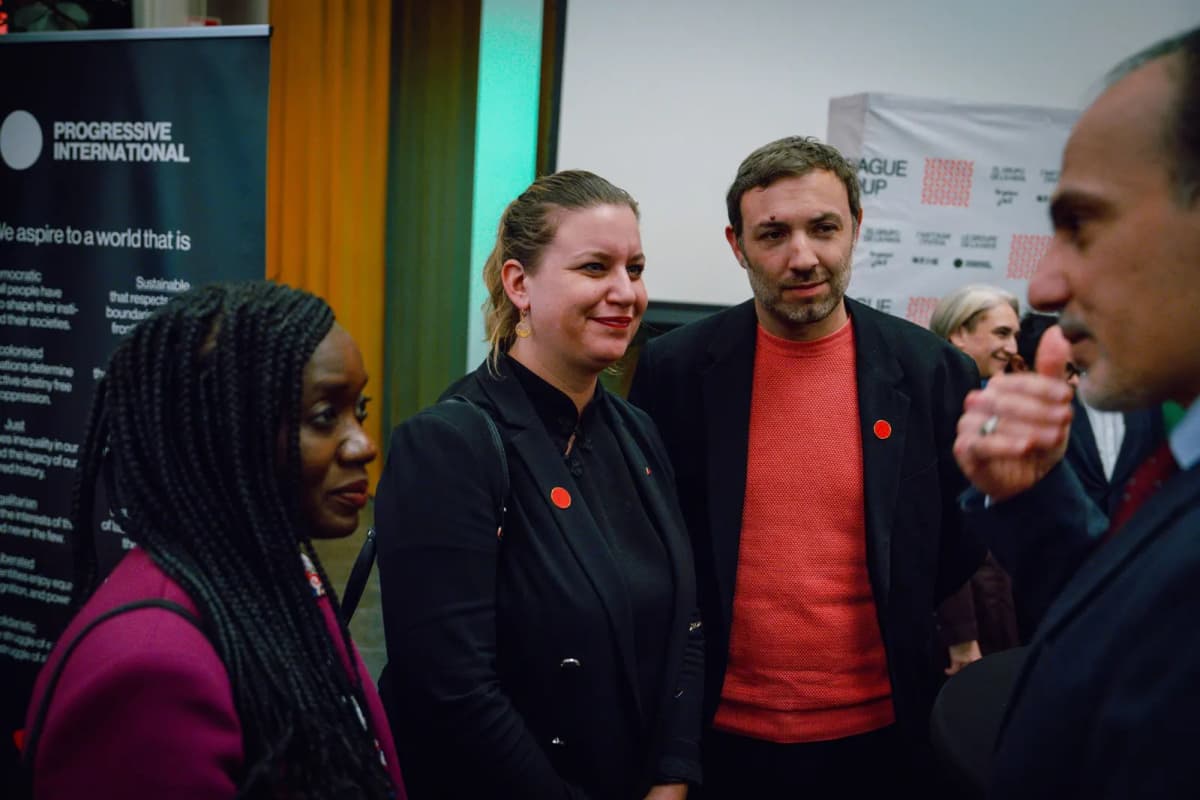 Trois personnes en conversation devant un kakémono lors d’une rencontre internationale.