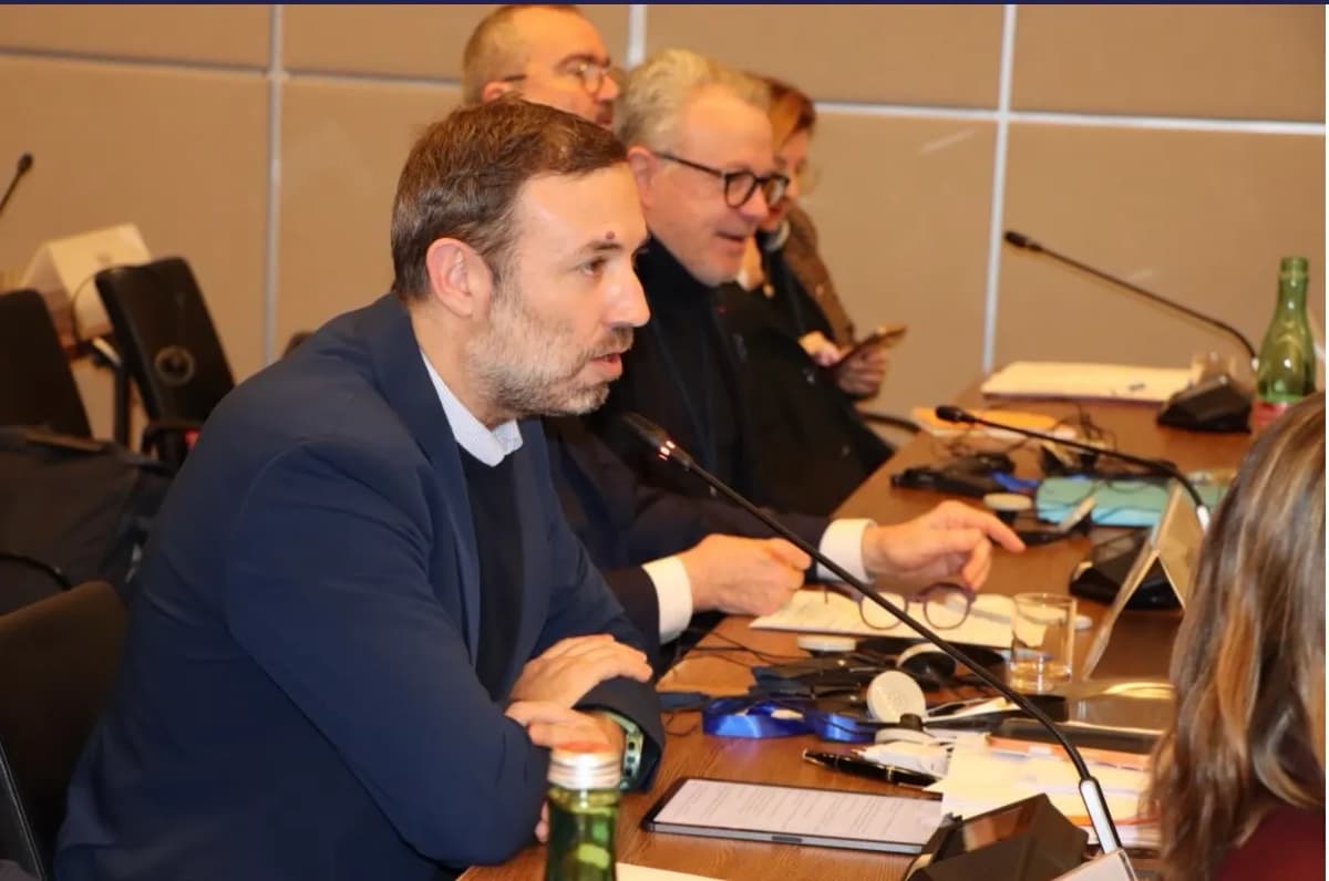 Députés attablés en salle de commission, micros et documents devant eux.