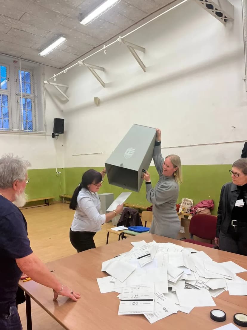 Dépouillement dans un bureau de vote : une urne renversée au-dessus d’une table couverte de bulletins.