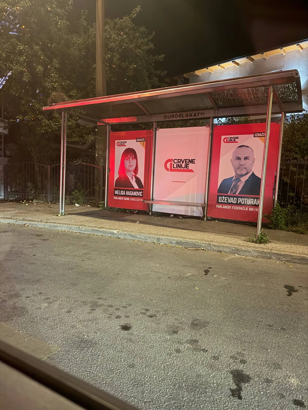 De nuit, un abribus couvert d’affiches électorales rouges de deux candidats.
