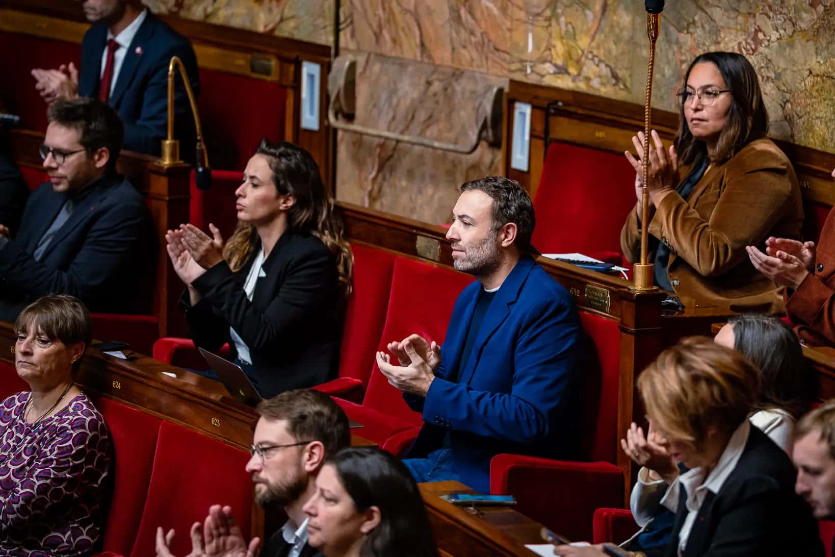 Thomas Portes applaudit depuis son banc dans l’hémicycle de l’Assemblée nationale, entouré de députés.
